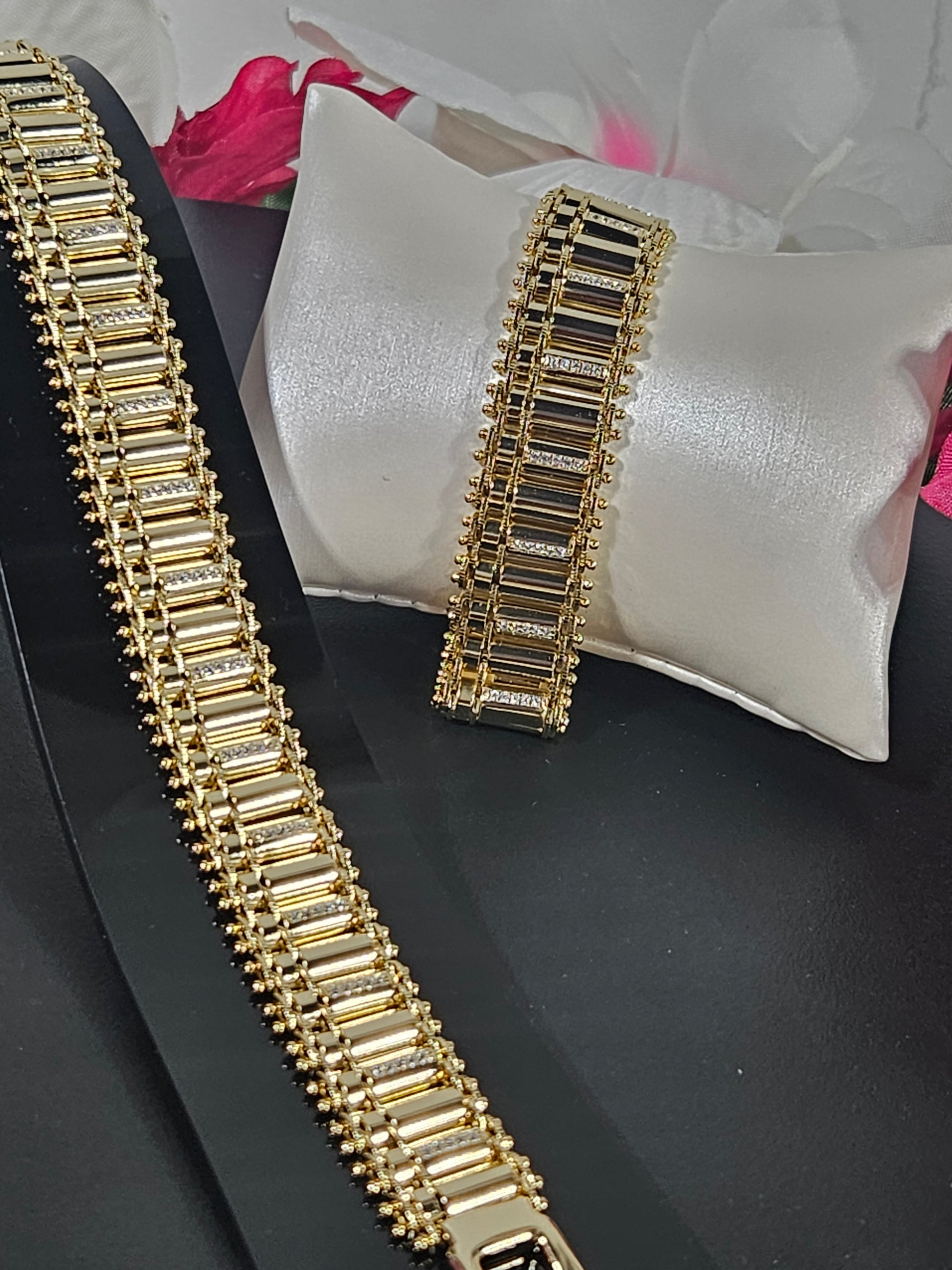 Gold bracelet on a black surface with a white pillow