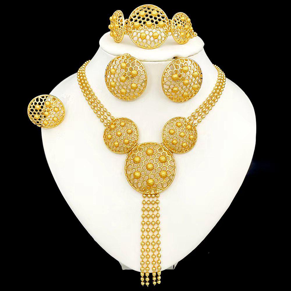Gold jewelry set including necklace, earrings, and bracelet on a white stand.