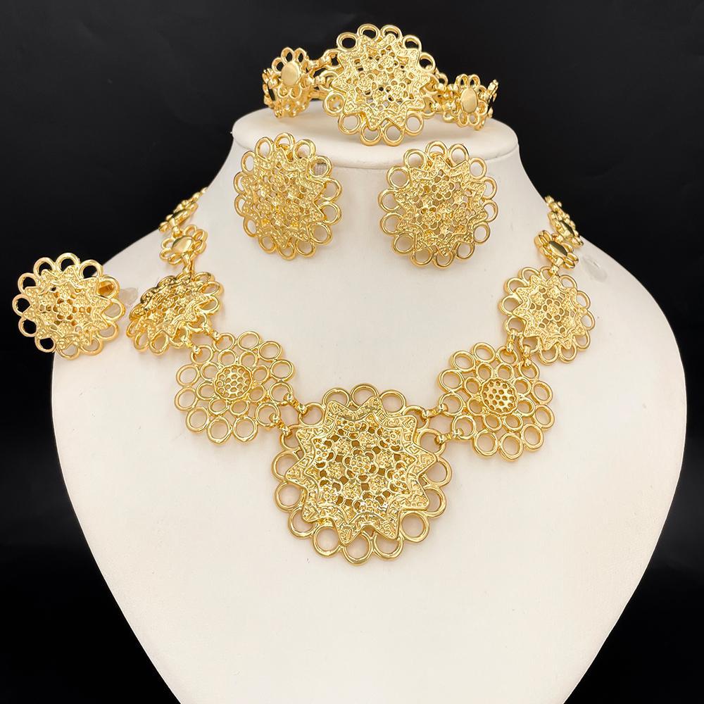 Gold jewelry set including necklace, earrings, and bracelet on a white stand with a black background