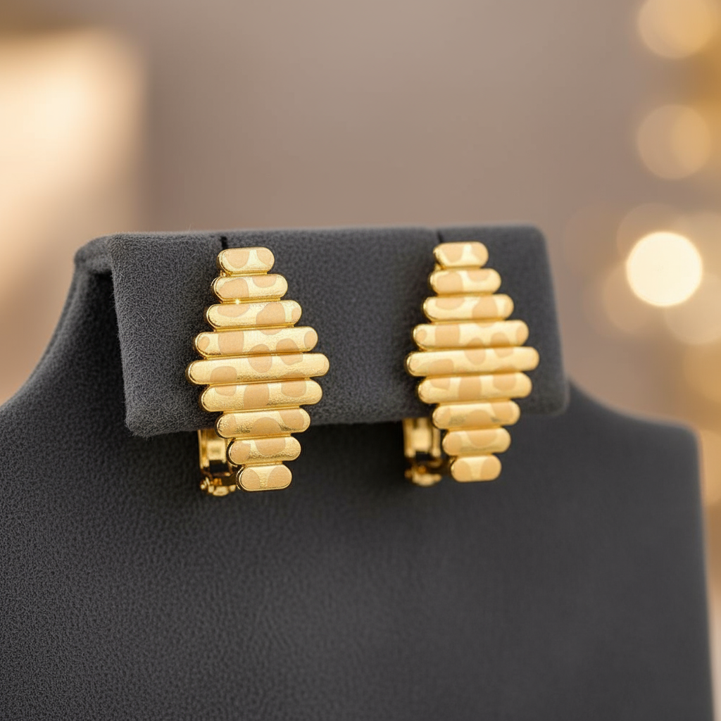 Gold earrings on a black stand with a blurred background