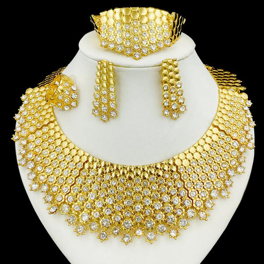 Gold jewelry set with necklace, earrings, and bracelet on a white stand against a black background