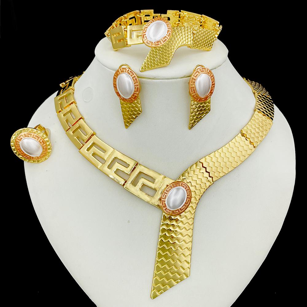 Gold jewelry set with necklace, earrings, and bracelet on a white stand against a black background