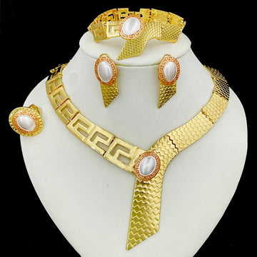 Gold jewelry set with necklace, earrings, and bracelet on a white stand against a black background