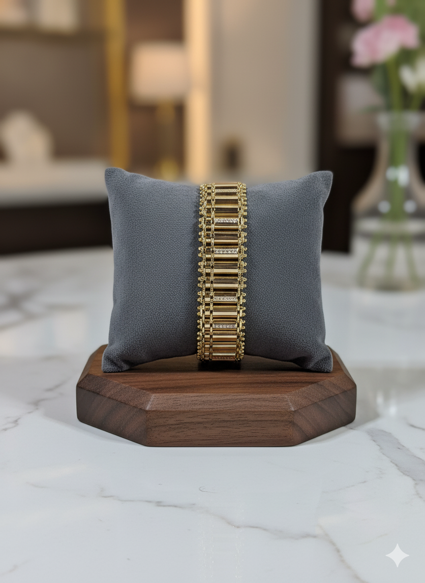 Gold bracelet on a gray pillow with a wooden base, blurred indoor background