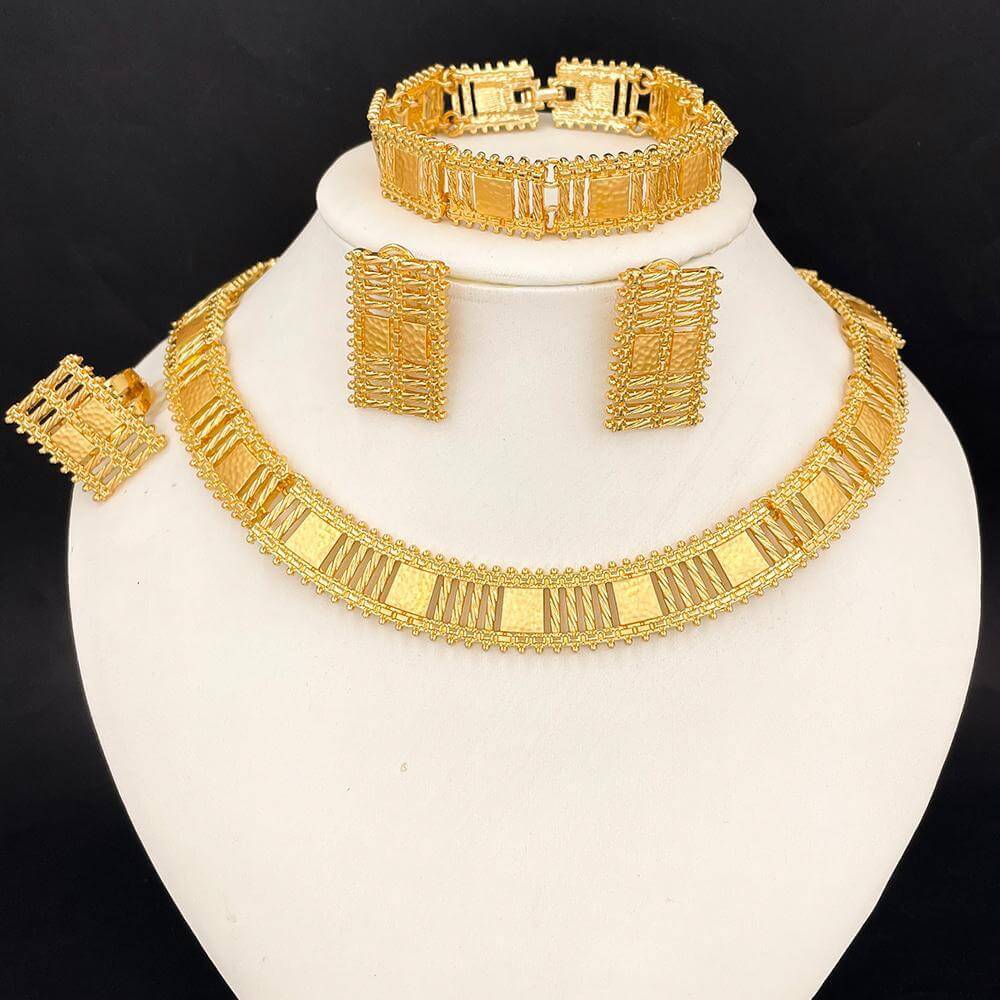 Gold jewelry set including necklace, earrings, and bracelet on a white stand with a black background.