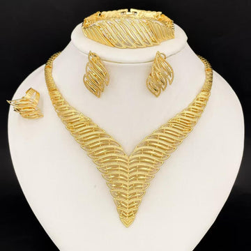 Gold jewelry set including necklace, earrings, and bracelet on a white stand with a black background
