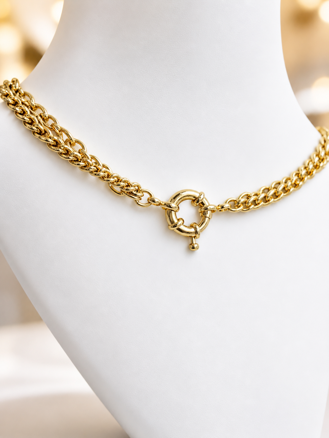 Gold chain necklace on a mannequin bust with a blurred background