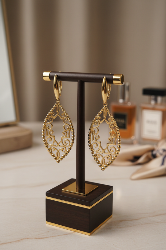 Gold earrings on a black stand with a blurred background