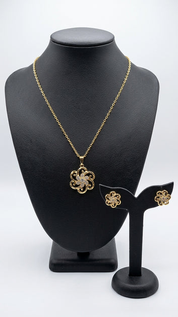 Gold necklace and earrings on a black mannequin bust with a white background