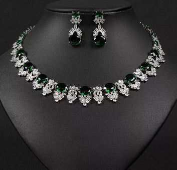 Jewelry set with necklace and earrings featuring green and clear stones on a black background