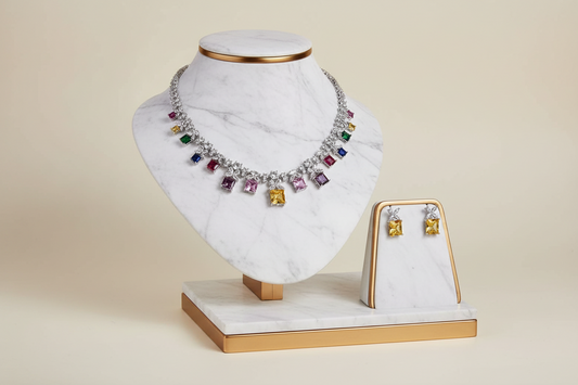Jewelry set with a necklace and earrings on a white marble stand with gold accents.