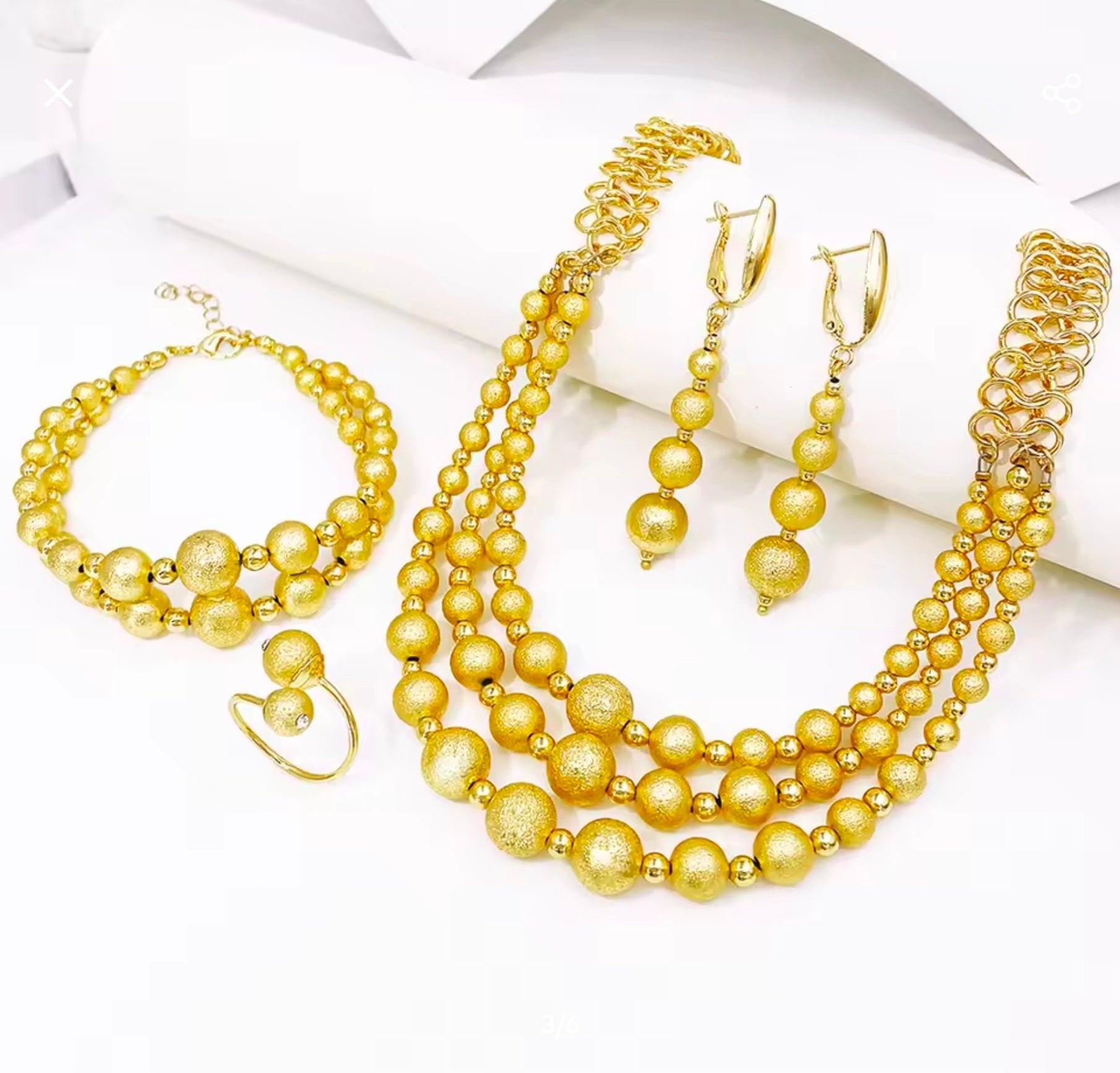 Gold pearl jewelry set including necklace, bracelet, and earrings on a white background