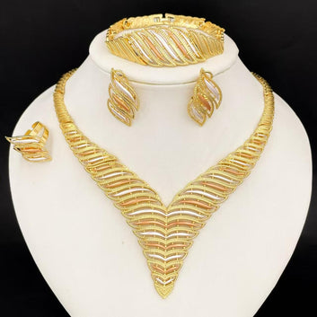 Gold jewelry set including necklace, earrings, and bracelet on a white stand with a black background.