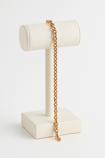 Gold chain on a white jewelry stand against a white background