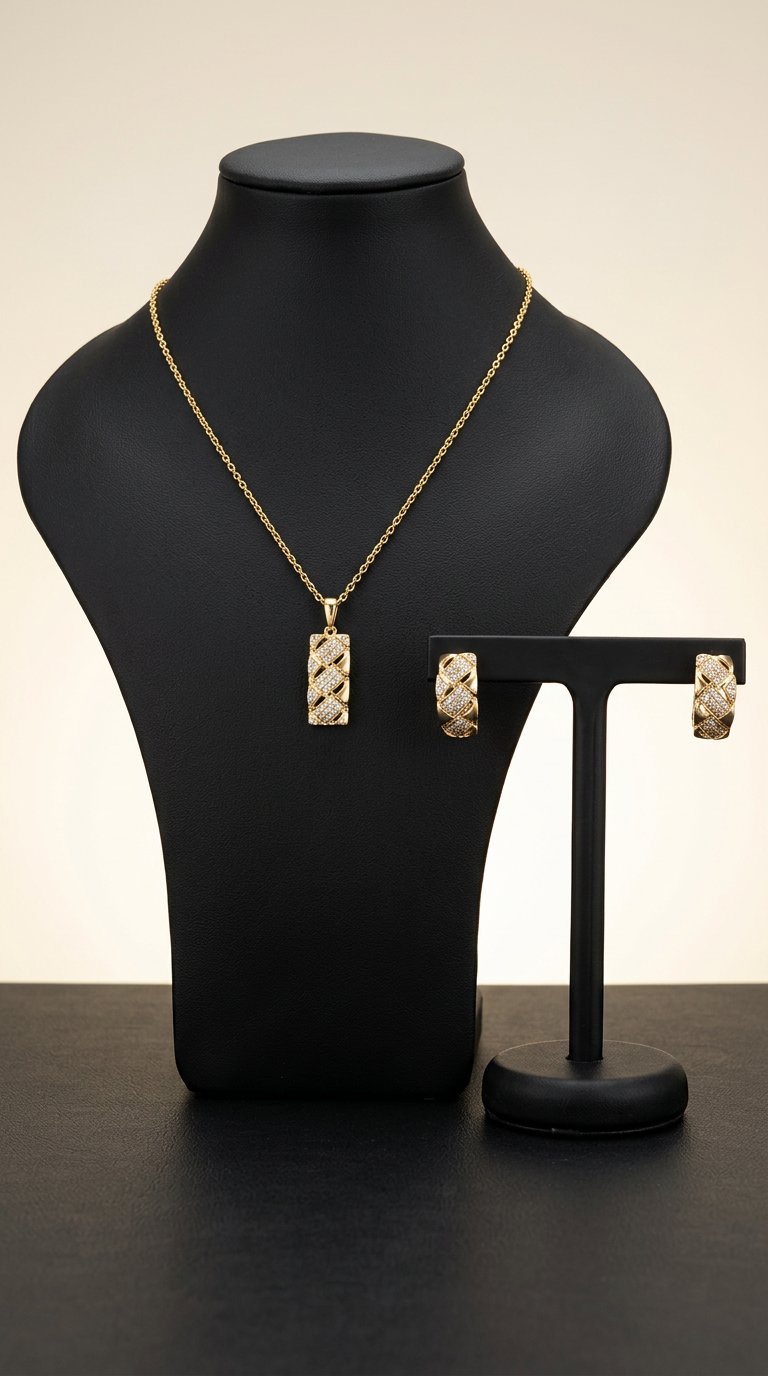 Gold necklace and earrings on a black mannequin and stand against a neutral background