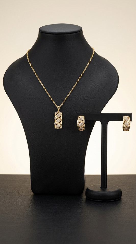 Gold necklace and earrings on a black mannequin and stand against a neutral background