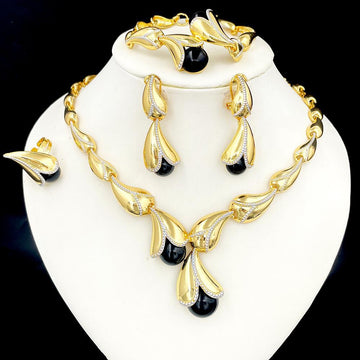 Gold and black jewelry set on a white stand with a black background